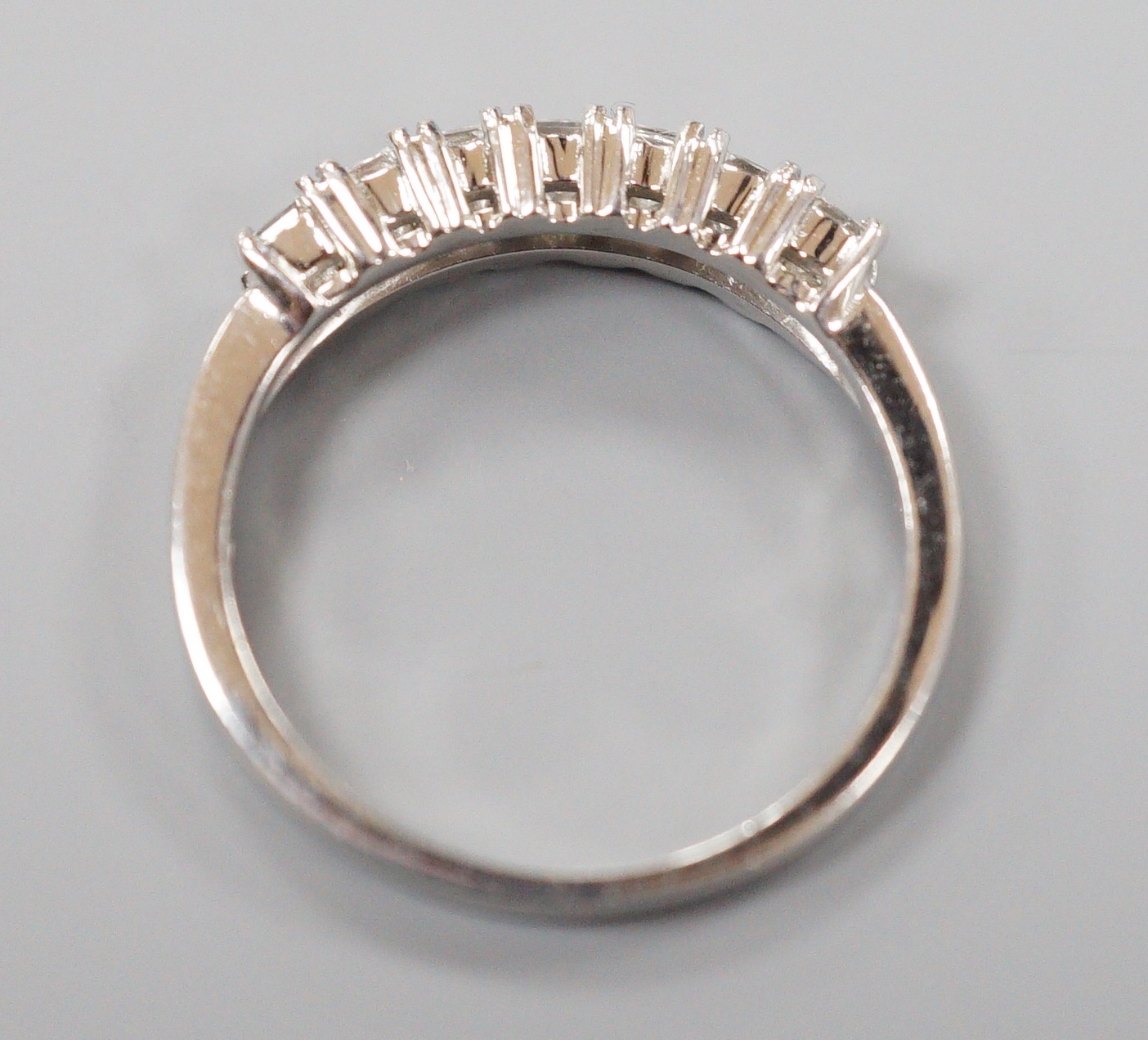 A modern platinum and seven stone princess cut diamond set half hoop ring, size M/N, gross weight 4 grams